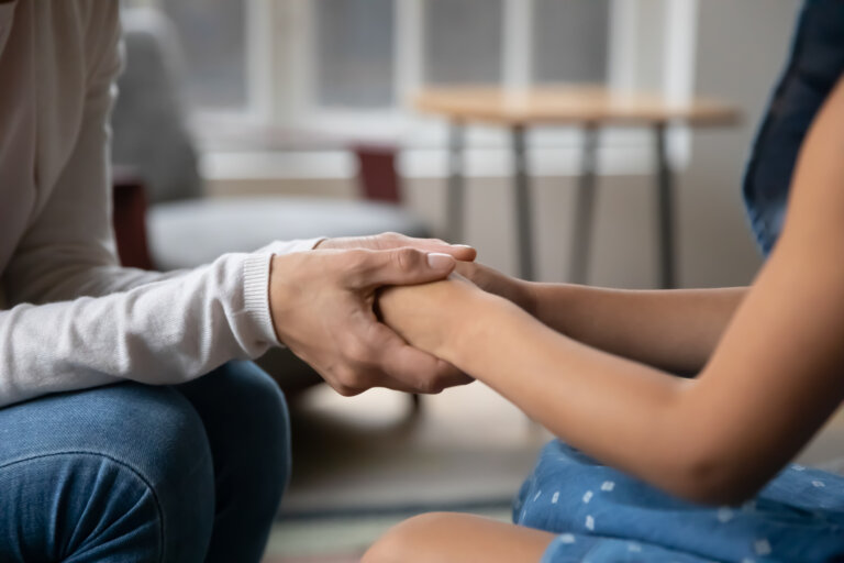 Close up of young mom hold little daughter hands talk share secrets make peace at home, mother and small daughter enjoy tender close moment family moment, show love care and gratitude in relationships