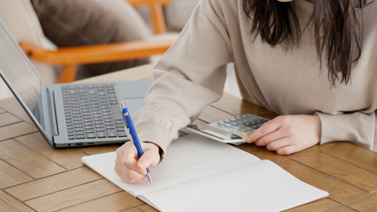 A woman calculating with a calculator and taking notes