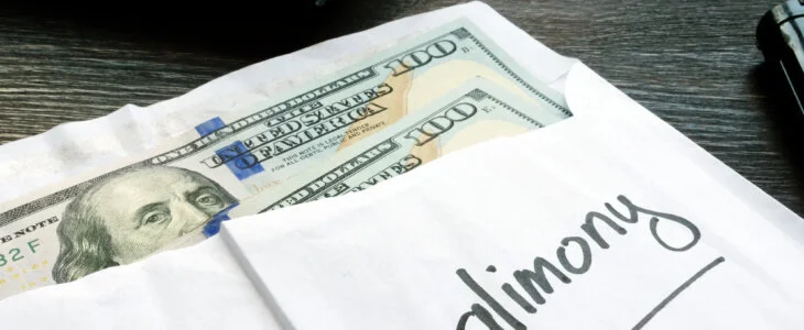 Alimony concept. Open envelope with cash on the wooden desk.