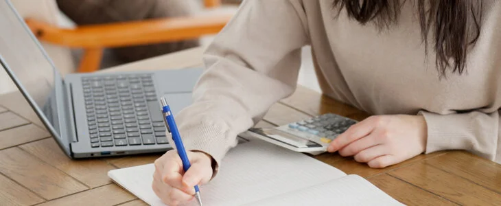 A woman calculating with a calculator and taking notes